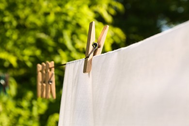 Photo of Washing line with clean laundry and clothespins outdoors, closeup