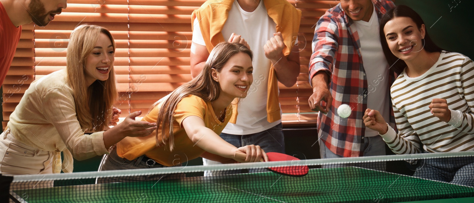 Image of Happy friends playing ping pong together indoors. Banner design