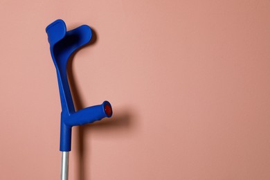 Photo of Elbow crutch on pale pink background. Space for text