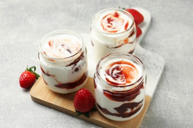 Photo of Tasty yoghurt with jam and strawberries on grey table, closeup