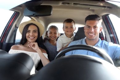 Photo of Happy family in car on road trip, view from outside