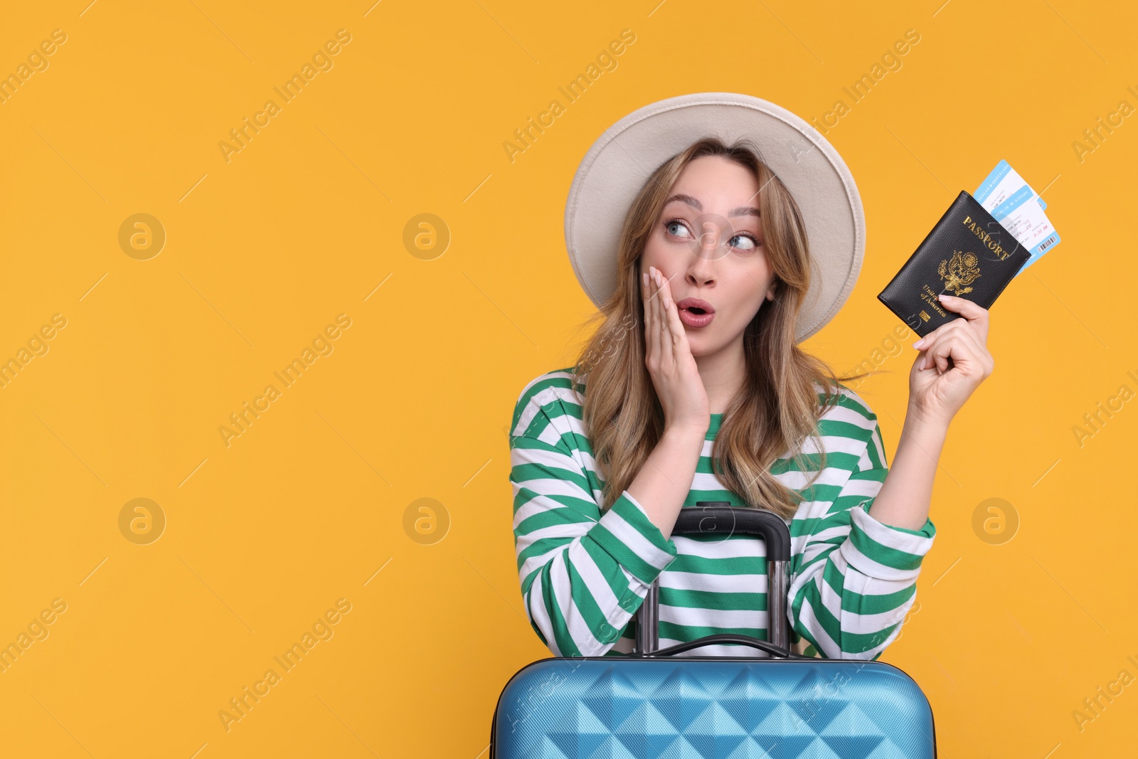 Photo of Happy young woman with passport, ticket and suitcase on yellow background, space for text