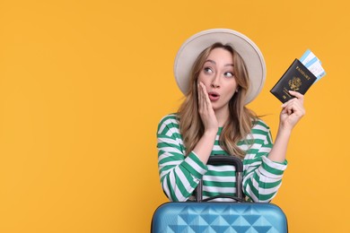 Happy young woman with passport, ticket and suitcase on yellow background, space for text