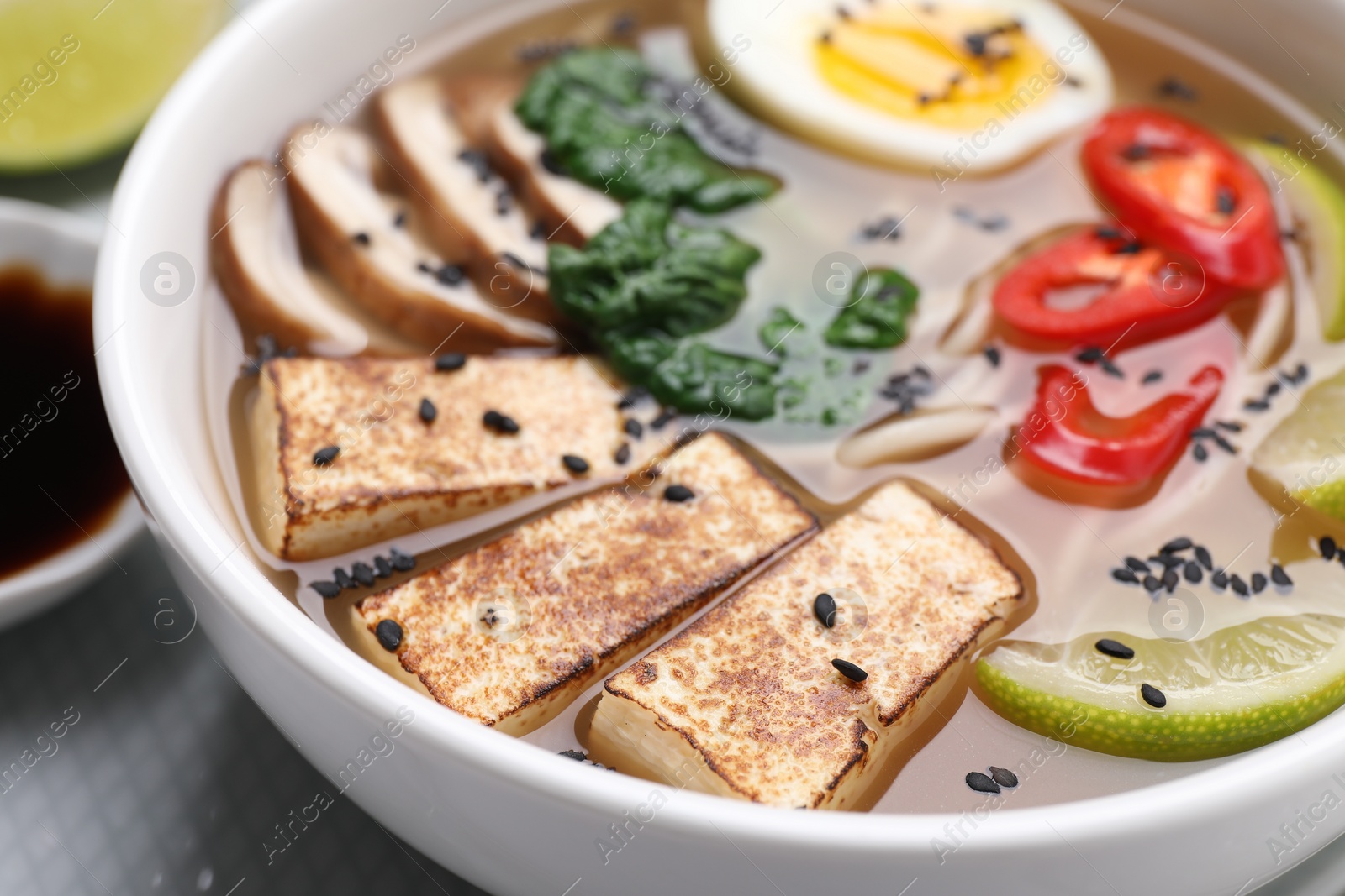 Photo of Delicious vegetarian ramen with tofu cheese in bowl, closeup