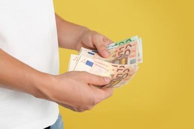 Photo of Man with Euro banknotes on yellow background, closeup