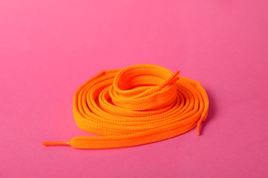 Photo of Orange shoe lace on pink background. Stylish accessory
