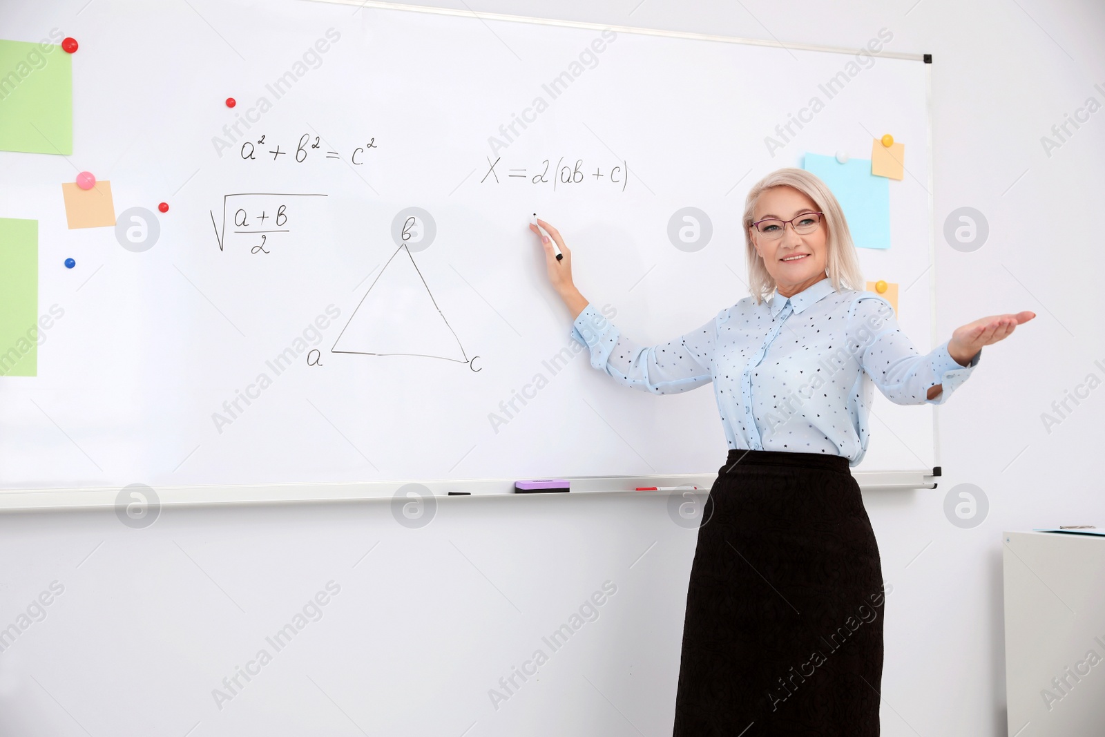 Photo of Mature teacher near whiteboard in modern classroom