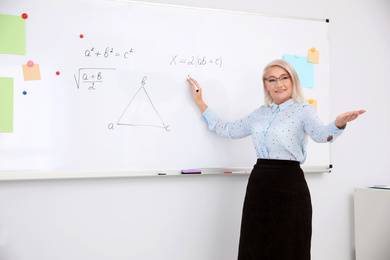 Mature teacher near whiteboard in modern classroom