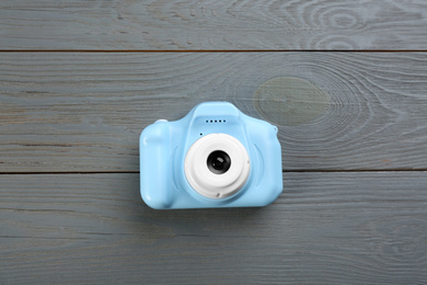 Light blue toy camera on grey wooden background, top view