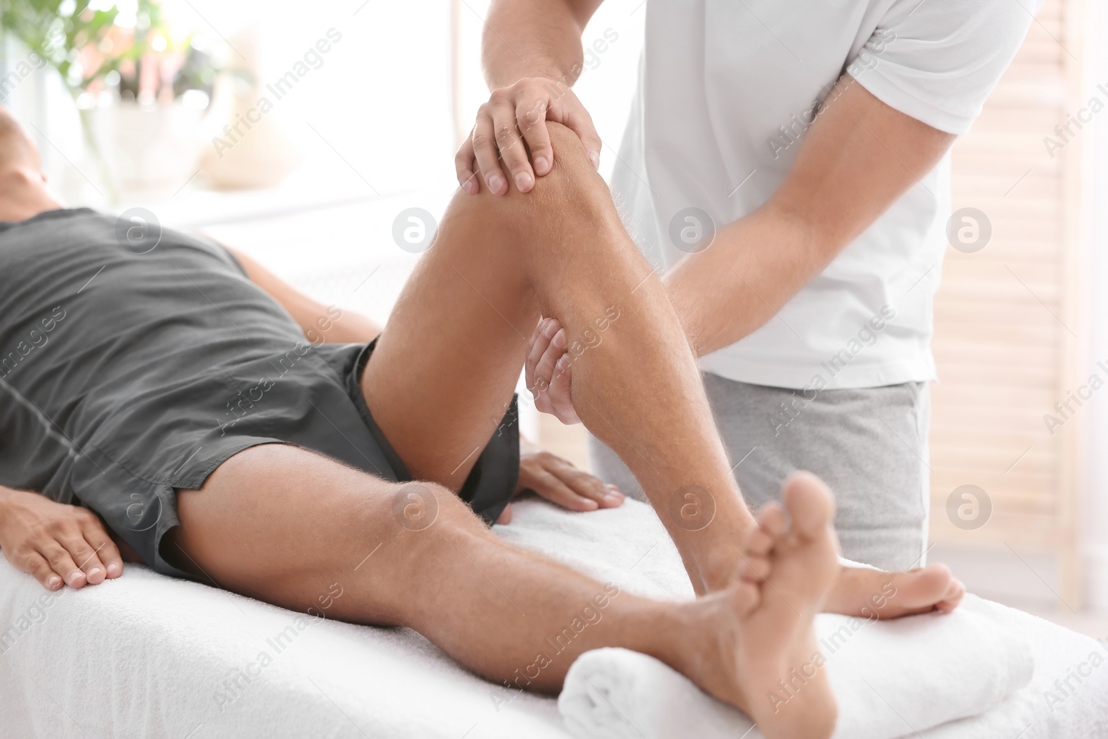 Photo of Young man receiving massage in salon, closeup