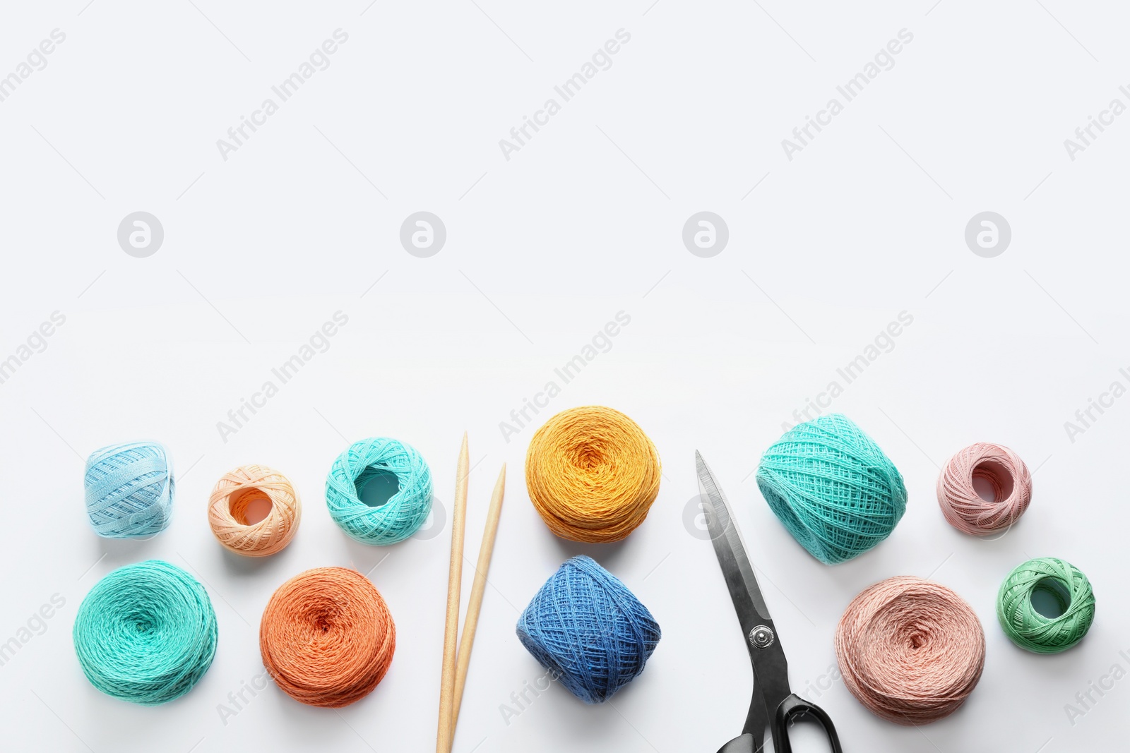 Photo of Composition with clews of colorful knitting threads and accessories on white background, top view