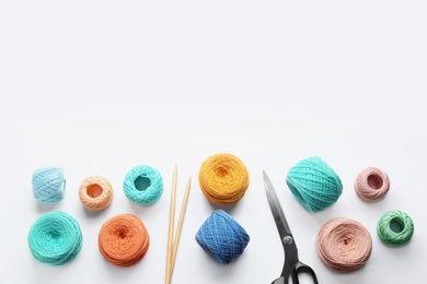 Composition with clews of colorful knitting threads and accessories on white background, top view
