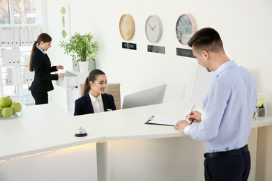 Young man filling form at reception desk in hotel