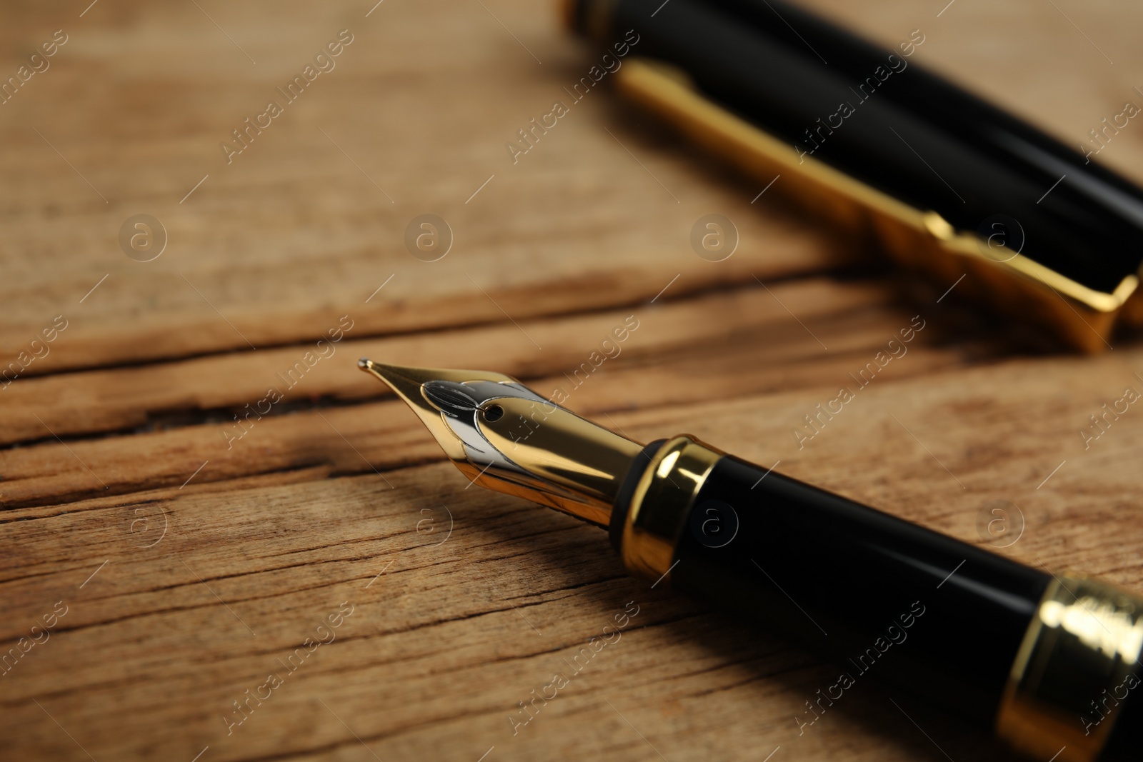 Photo of Beautiful fountain pen with ornate nib on wooden table, closeup
