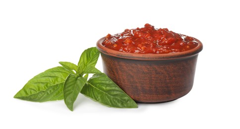 Delicious adjika sauce in bowl and basil isolated on white