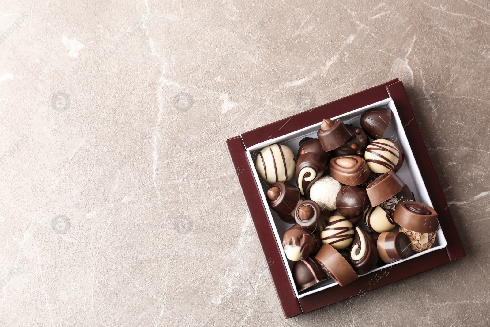 Photo of Box with different tasty chocolate candies on table, top view