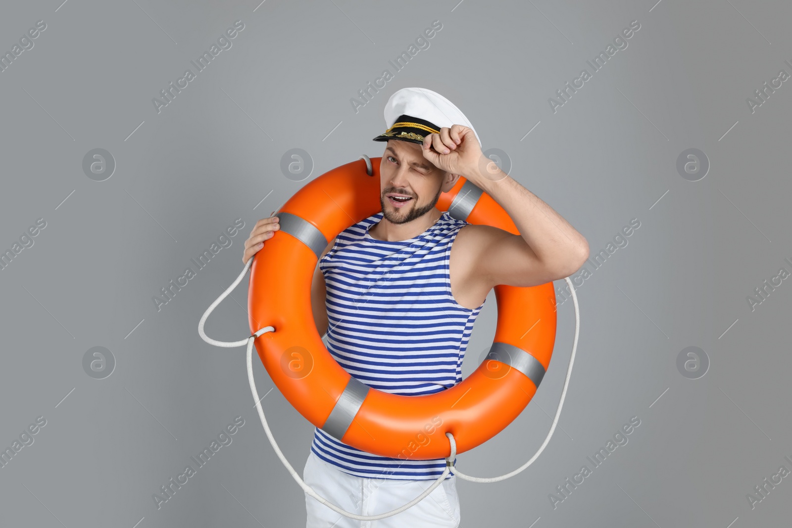 Photo of Sailor with orange ring buoy on grey background