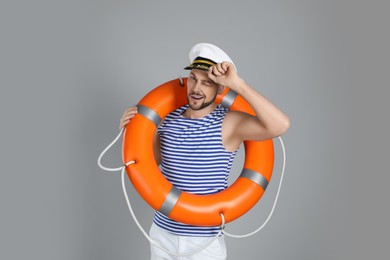 Sailor with orange ring buoy on grey background