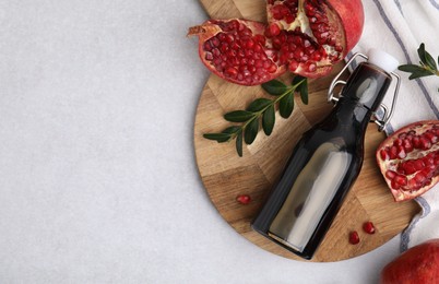 Photo of Tasty pomegranate sauce in bottle, branches and fruits on light table, flat lay. Space for text