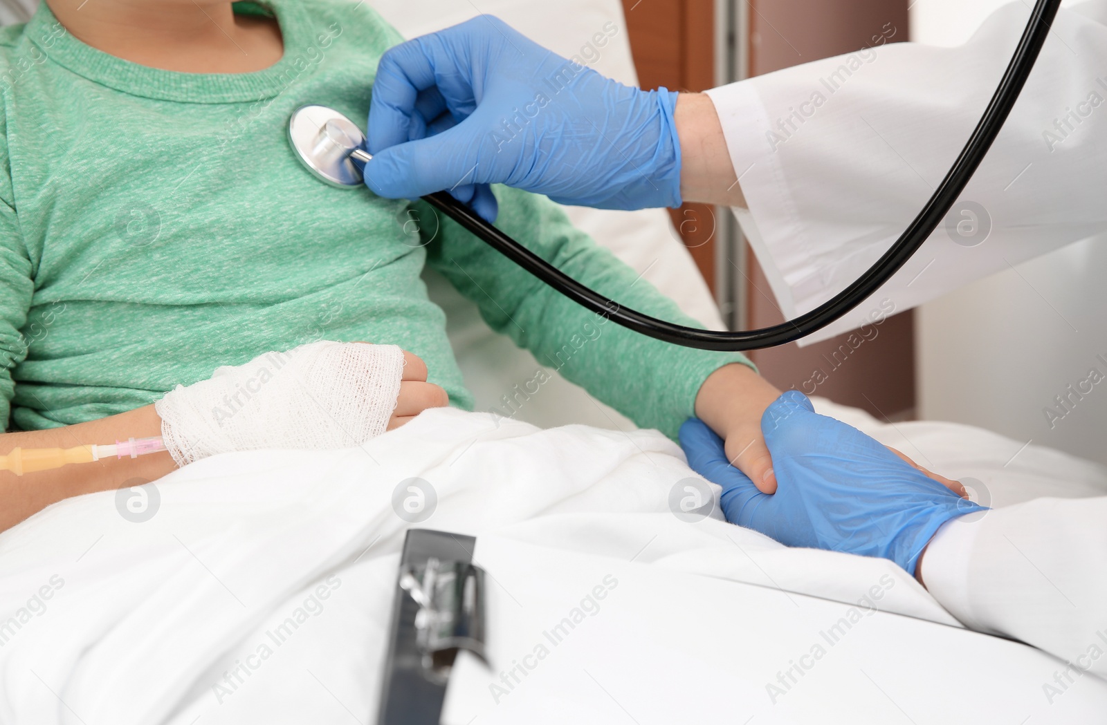 Photo of Doctor examining little child with stethoscope in hospital, closeup