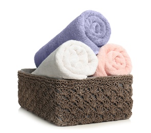 Photo of Rolled soft terry towels in wicker basket on white background