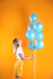 Photo of Young woman with air balloons on color background