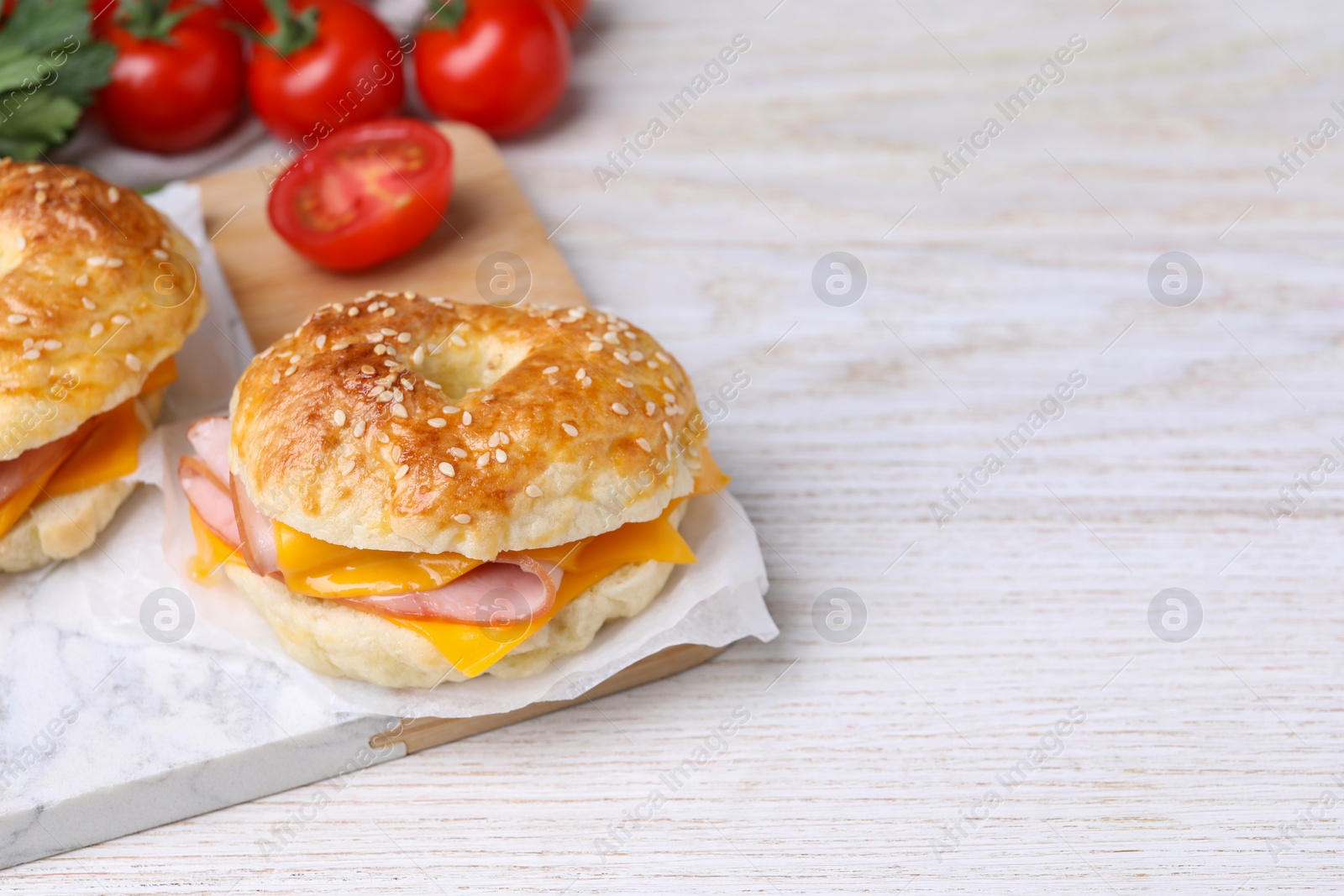 Delicious bagels with ham, cheese and products on white wooden table. Space for text Photo of Delicious bagels with ham, cheese and products on white wooden table. Space for text