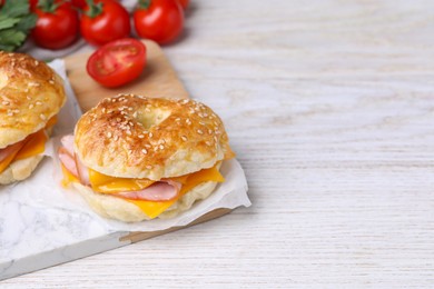 Photo of Delicious bagels with ham, cheese and products on white wooden table. Space for text