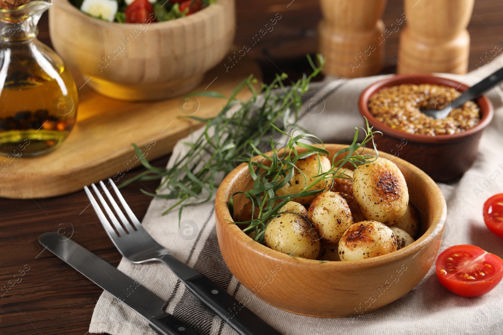 Photo of Delicious grilled potatoes with tarragon served on wooden table