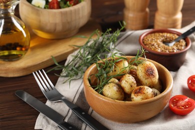 Delicious grilled potatoes with tarragon served on wooden table