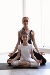 Photo of Little girl and her teacher practicing yoga in gym