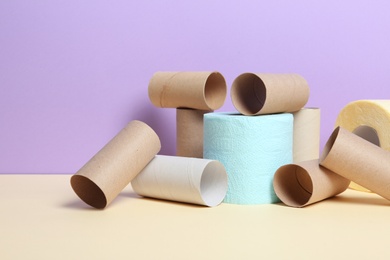 Photo of Full and empty toilet paper rolls on table against color background