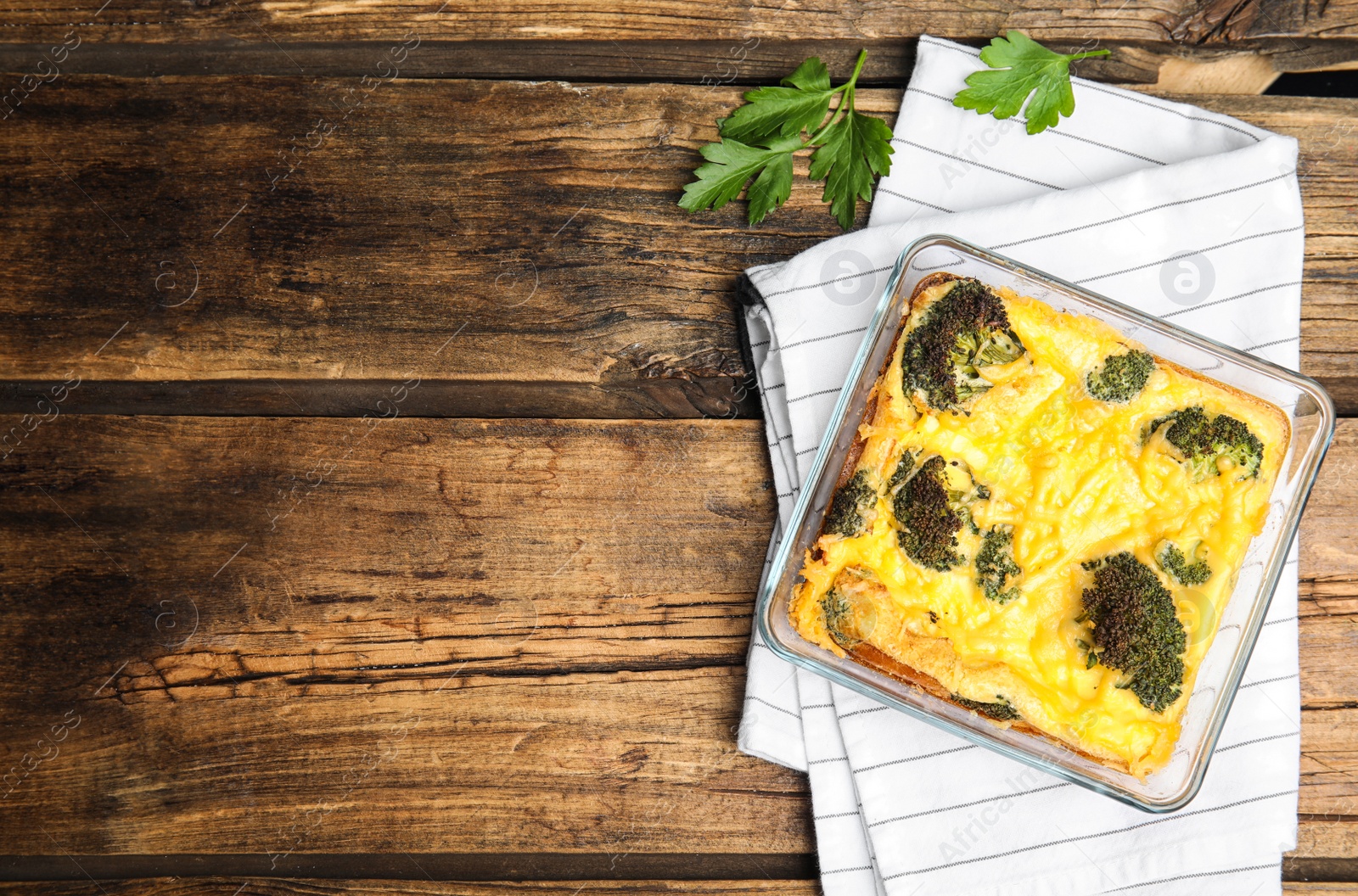 Photo of Tasty broccoli casserole in baking dish on wooden table, flat lay. Space for text