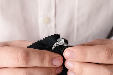Jeweler cleaning diamond ring with microfiber cloth, closeup