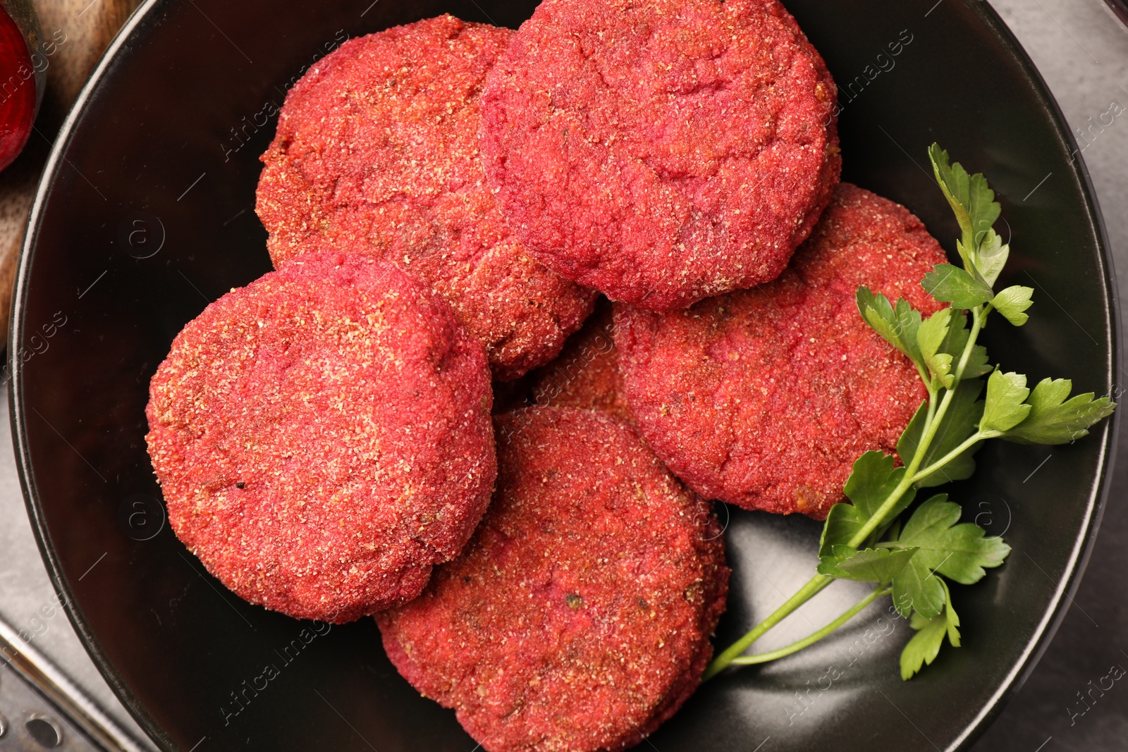 Photo of Delicious beetroot cutlets and parsley in black bowl, top view. Vegan dish