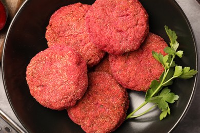 Photo of Delicious beetroot cutlets and parsley in black bowl, top view. Vegan dish