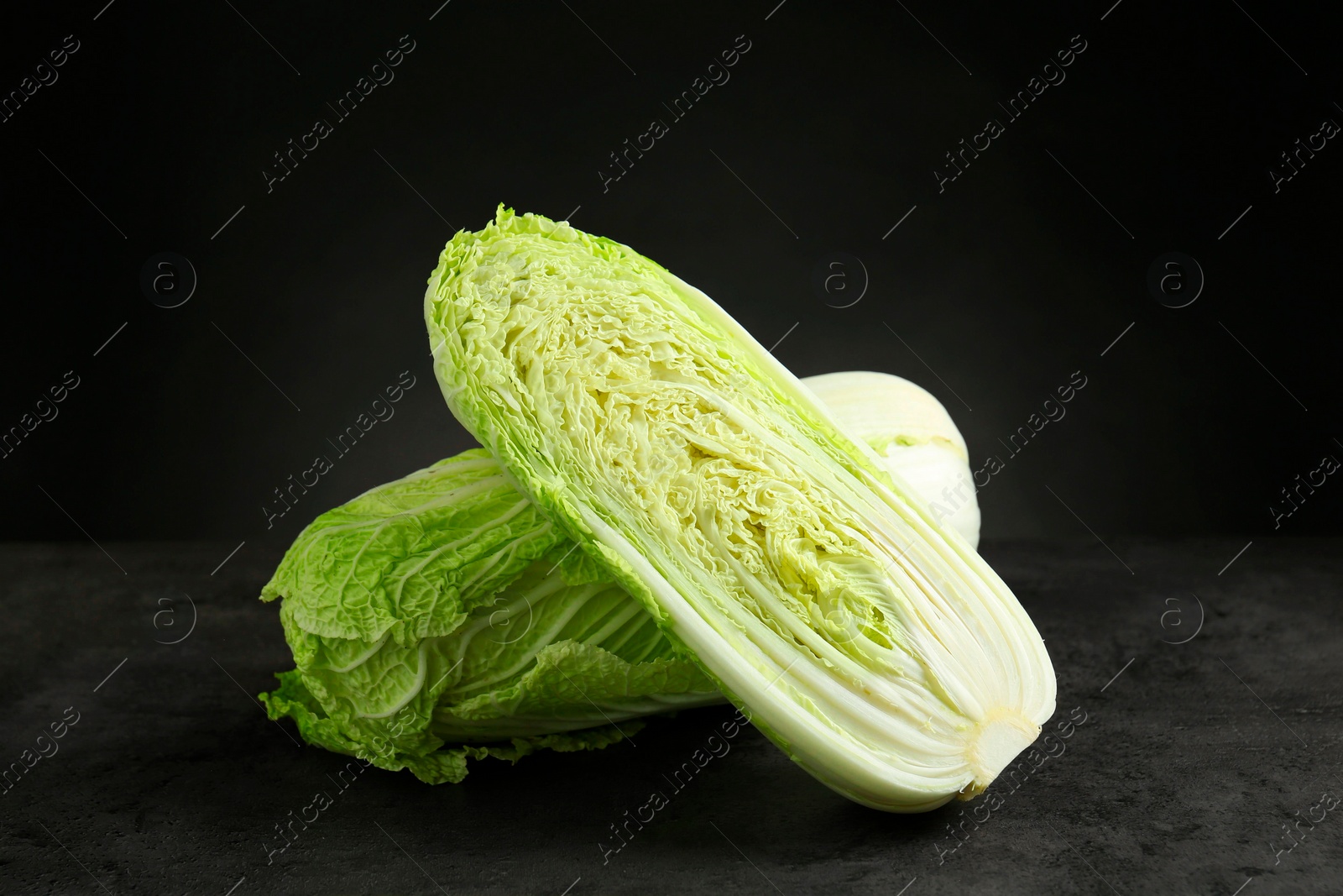 Photo of Whole and cut fresh Chinese cabbages on grey table