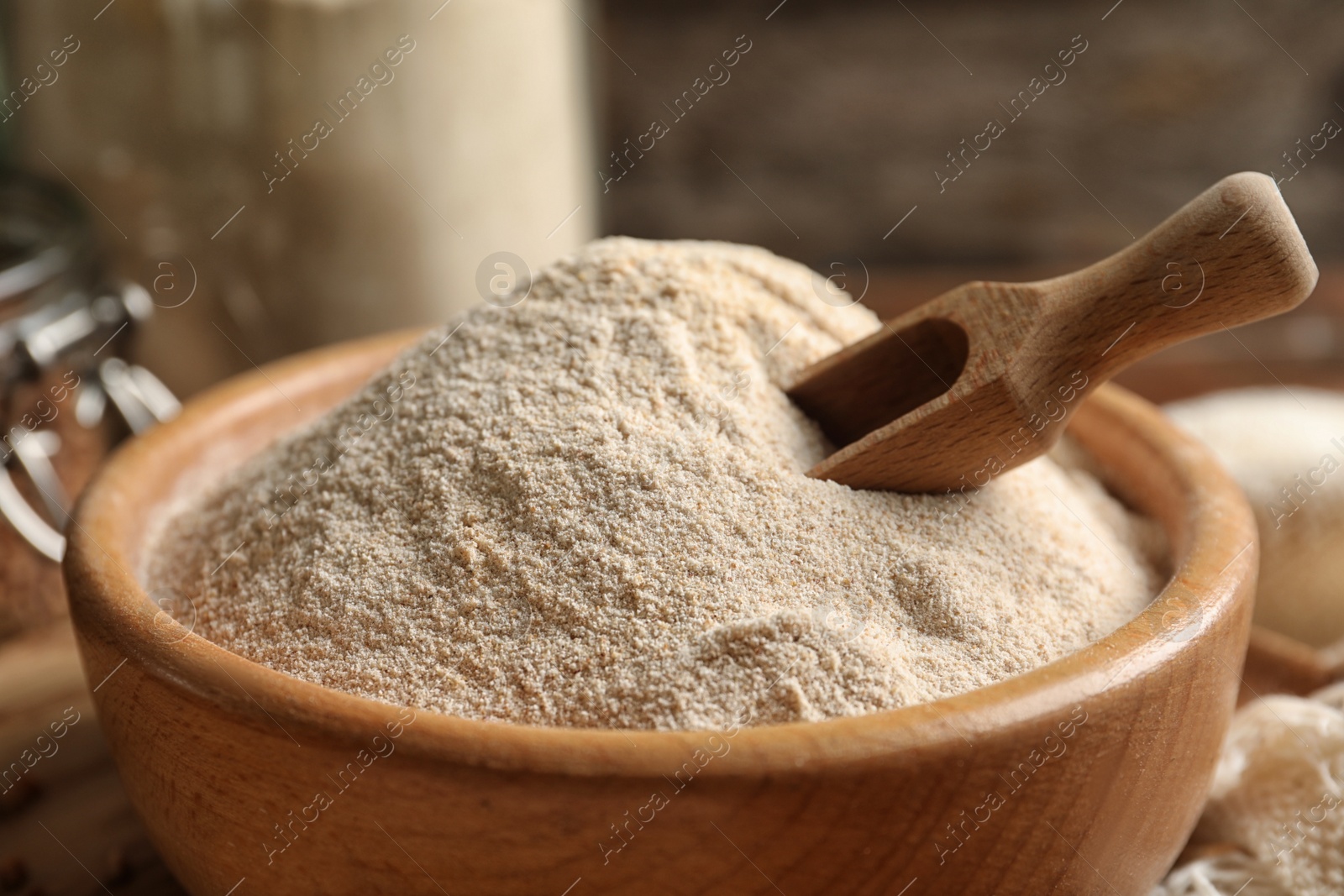 Image of Buckwheat flour in wooden bowl with scoop on table, closeup