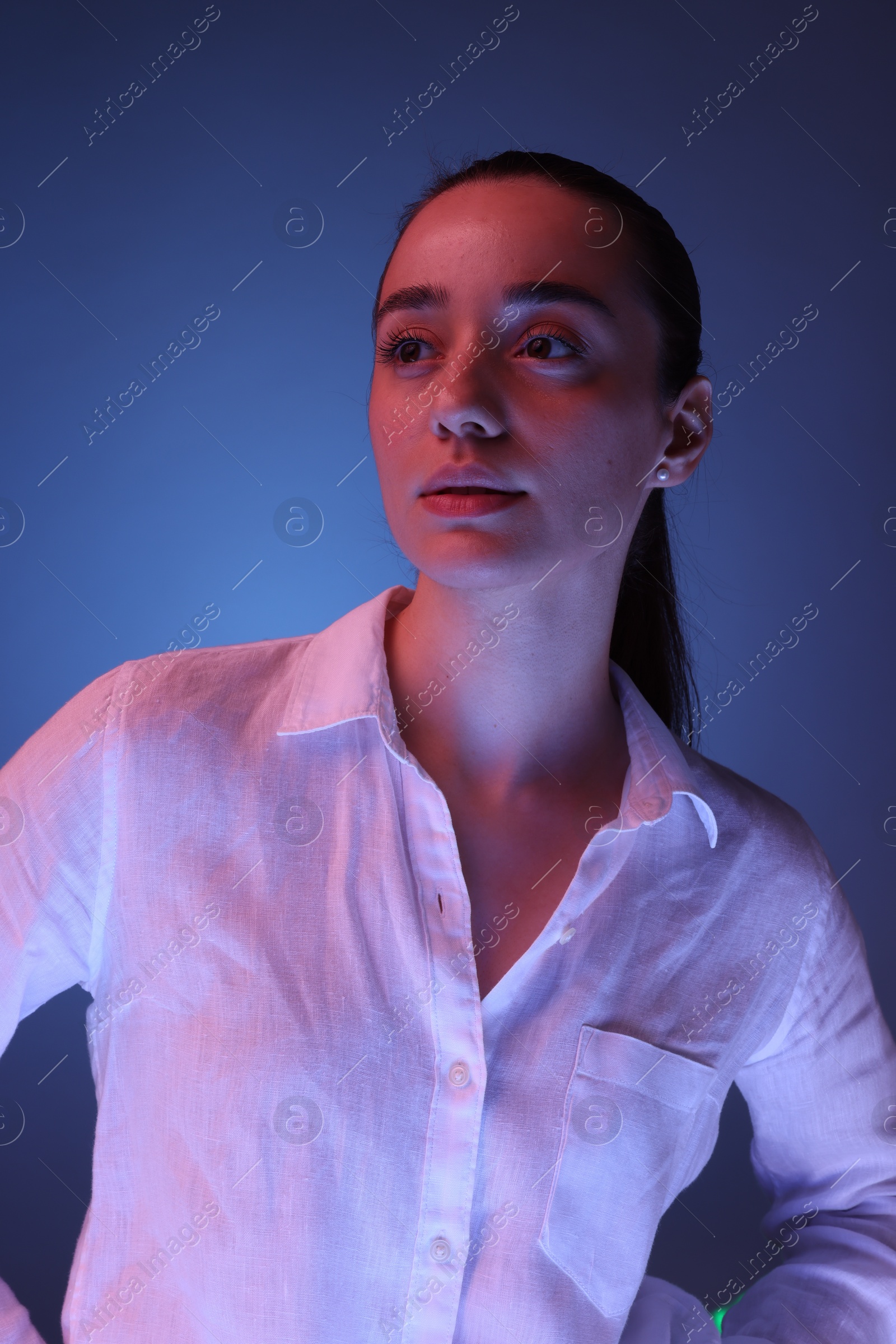 Photo of Portrait of beautiful young woman on blue background with neon lights