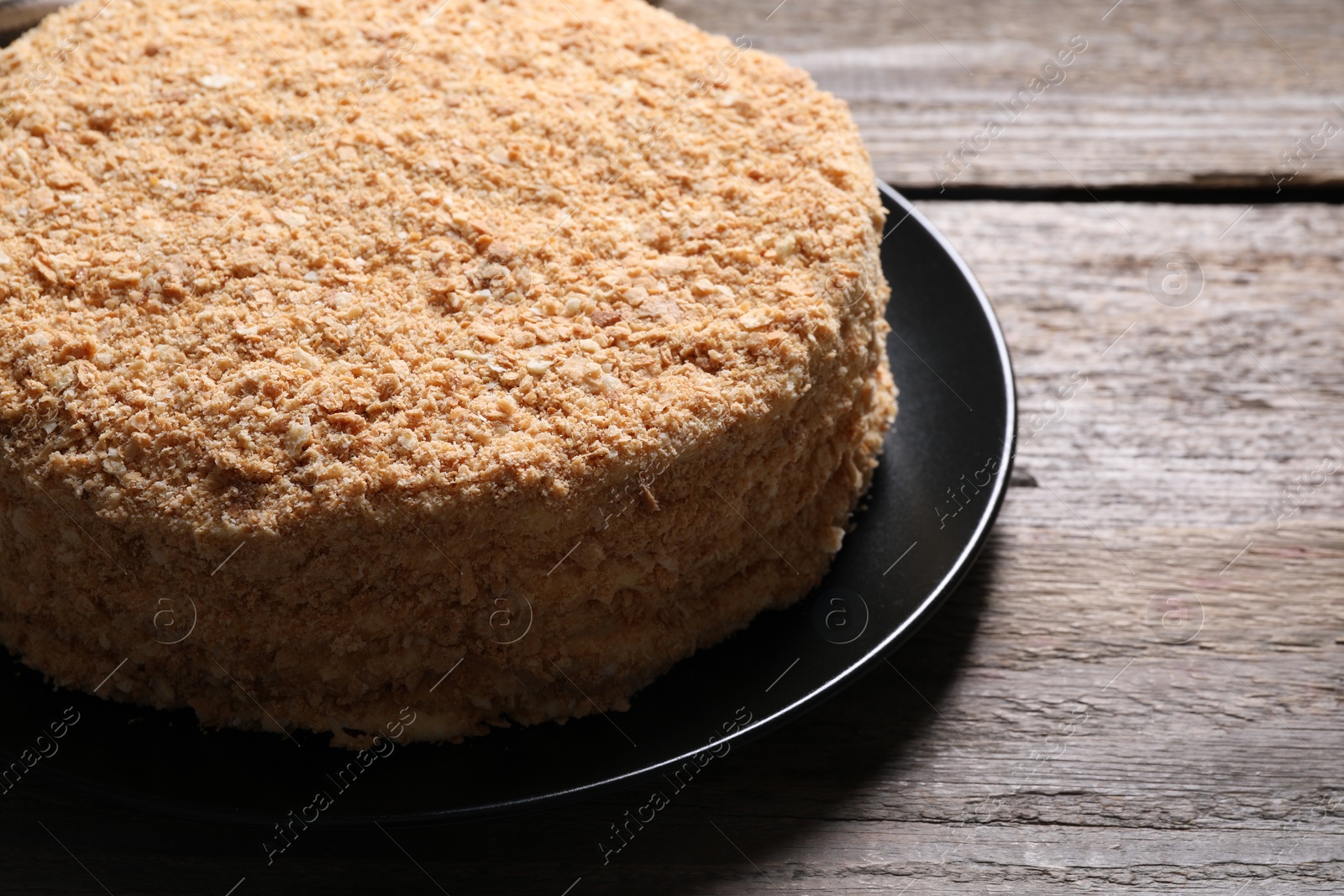 Photo of Delicious Napoleon cake on wooden table, closeup. Space for text