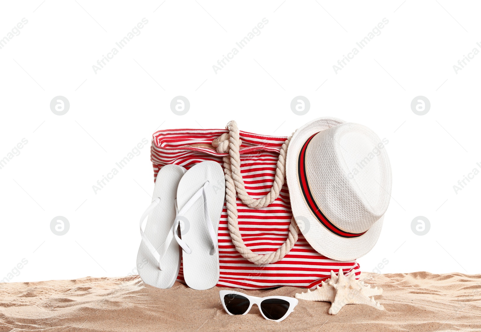 Photo of Stylish striped bag and beach accessories on sand against white background