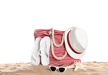 Stylish striped bag and beach accessories on sand against white background