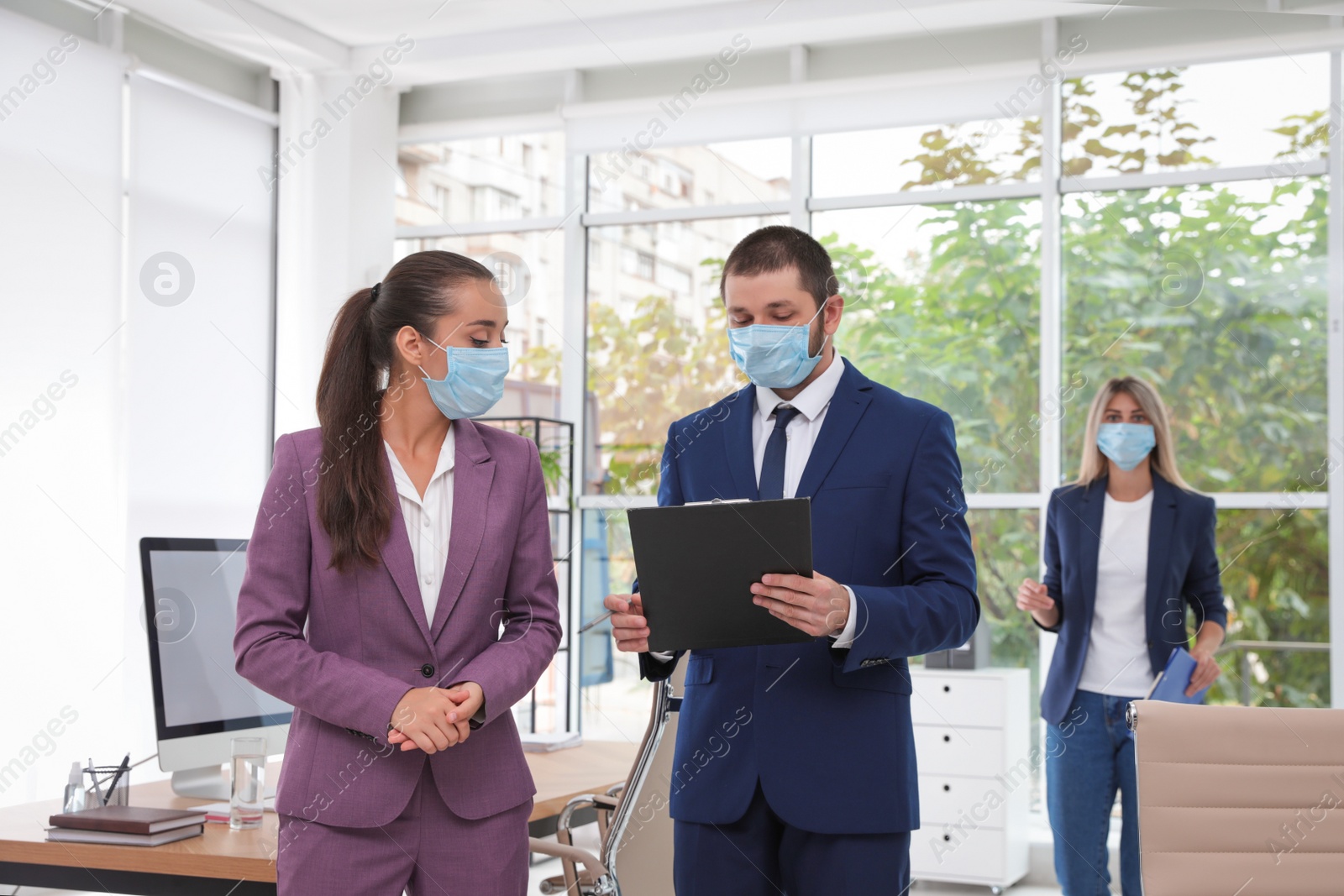 Photo of Office employees in respiratory masks at workplace