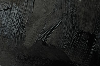 Photo of Beautiful strokes of black paint as background, closeup