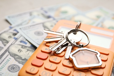 Keys with house trinket and calculator on money, closeup Real estate agent service