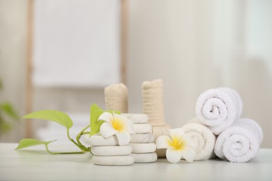 Composition with different spa products and plumeria flowers on white marble table indoors