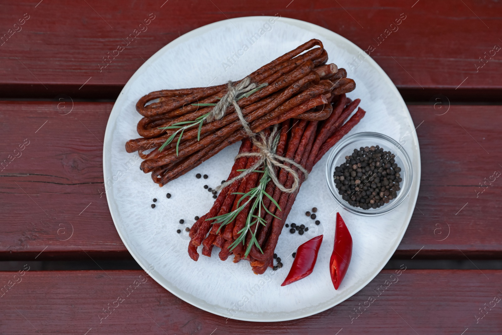 Photo of Tasty dry cured sausages (kabanosy) and ingredients on wooden table, top view