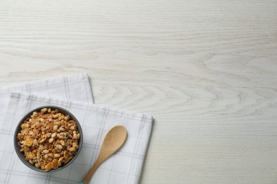 Ceramic bowl with granola on white wooden table, flat lay and space for text. Cooking utensils