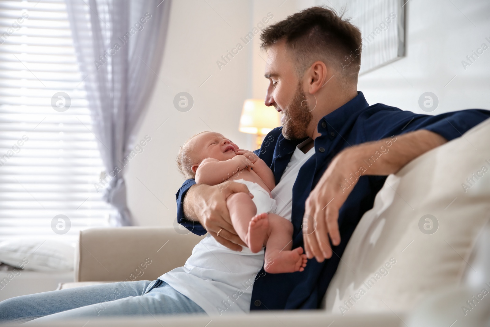 Photo of Father with his newborn son at home