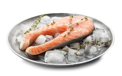 Plate with fresh raw salmon steak and ice cubes on white background